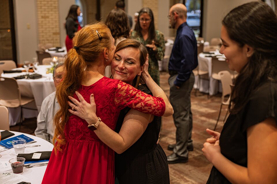 Two guests embracing in greeting among the tables