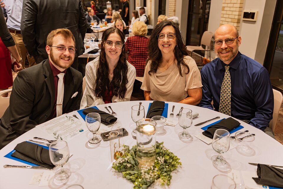 Four guests seated together at a candlelit banquet table