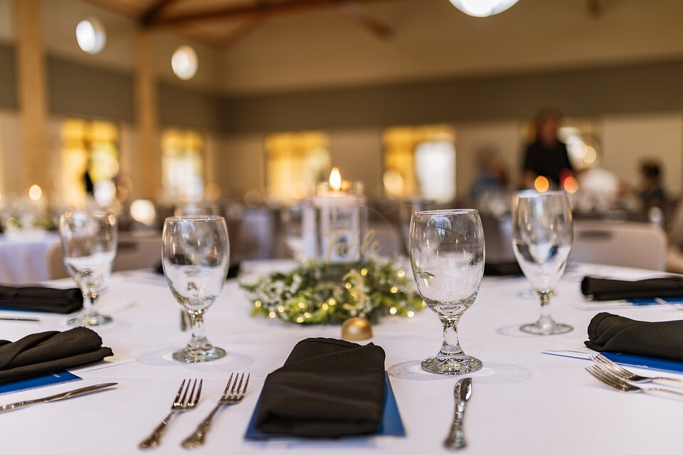 Place setting detail with candlelight and a greenery centerpiece