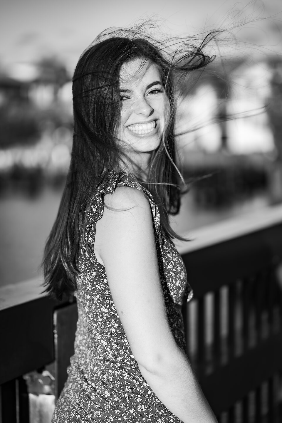Black and white portrait, hair caught in the wind on a waterfront deck