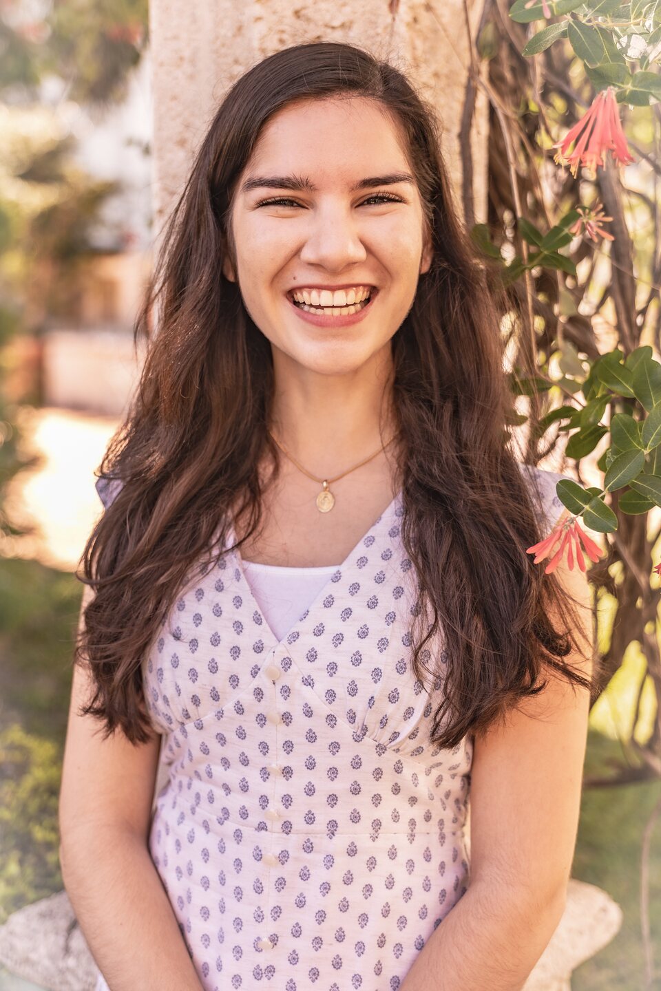 Young woman laughing against a stone column in evening garden light