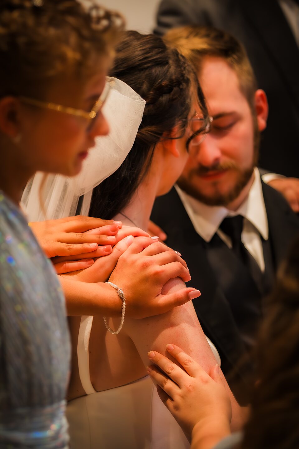 Hands resting on the bride and groom during a blessing