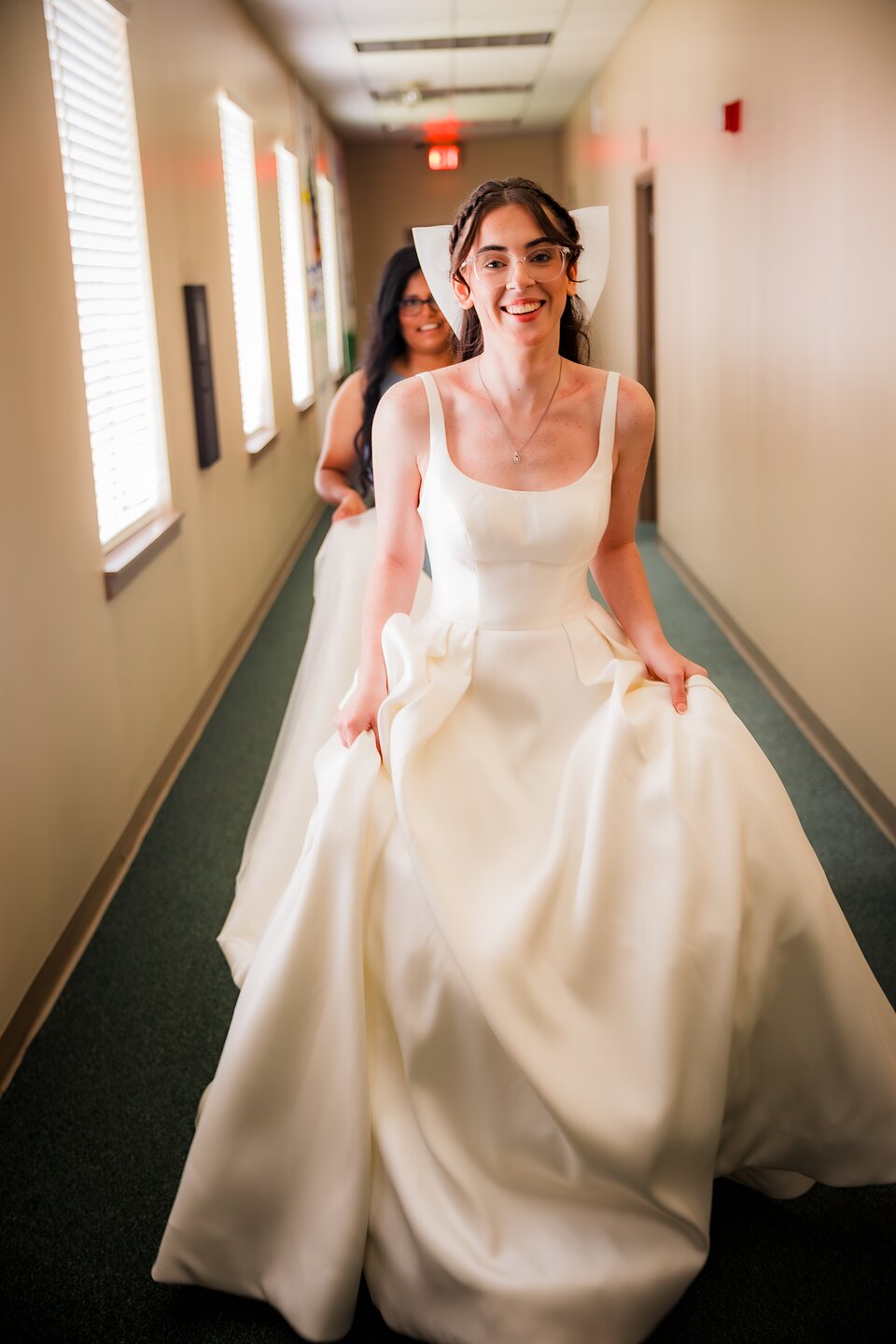 Bride gathering her gown as she walks a hallway before the ceremony