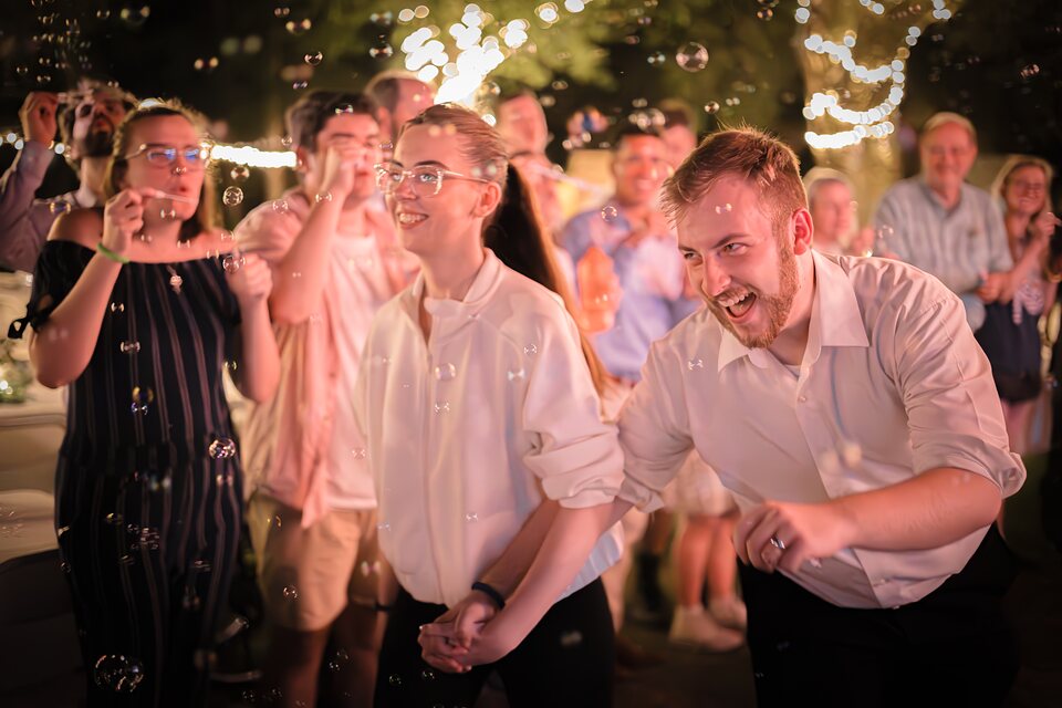 Guests blowing bubbles around the couple at an evening reception